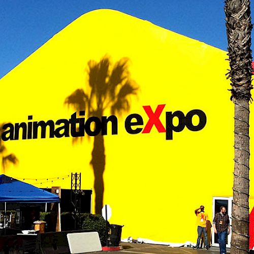 A large, yellow tent with "CTN animation eXpo" written on it. There are palm trees and some people gathered near the entrance.